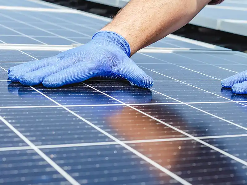 Gloved hands over solar panel